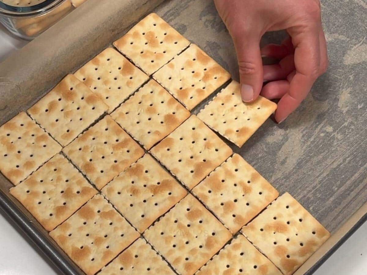 Laying saltine crackers in lined jelly roll pan.