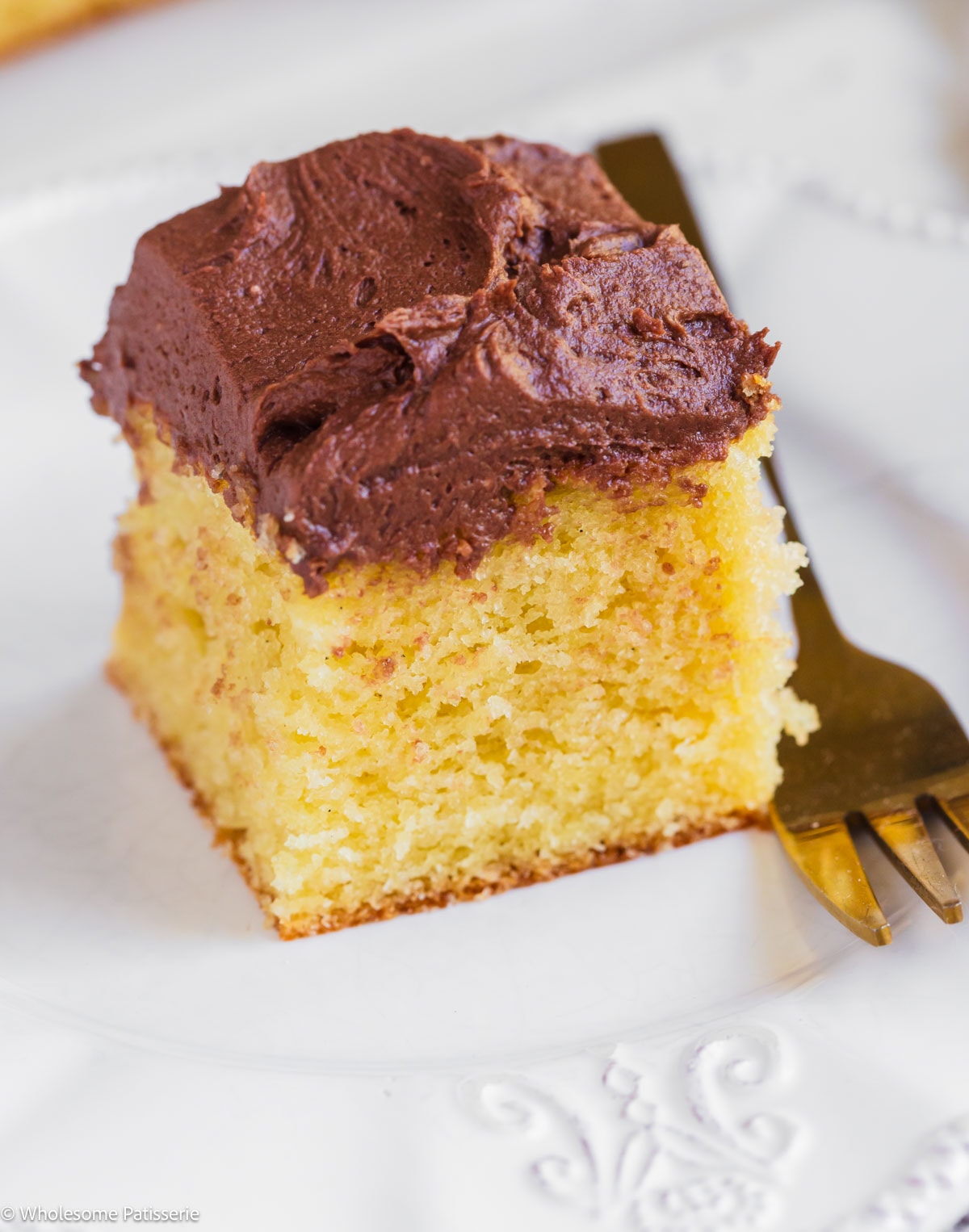 Slice of yellow cake without buttermilk on plate next to fork.