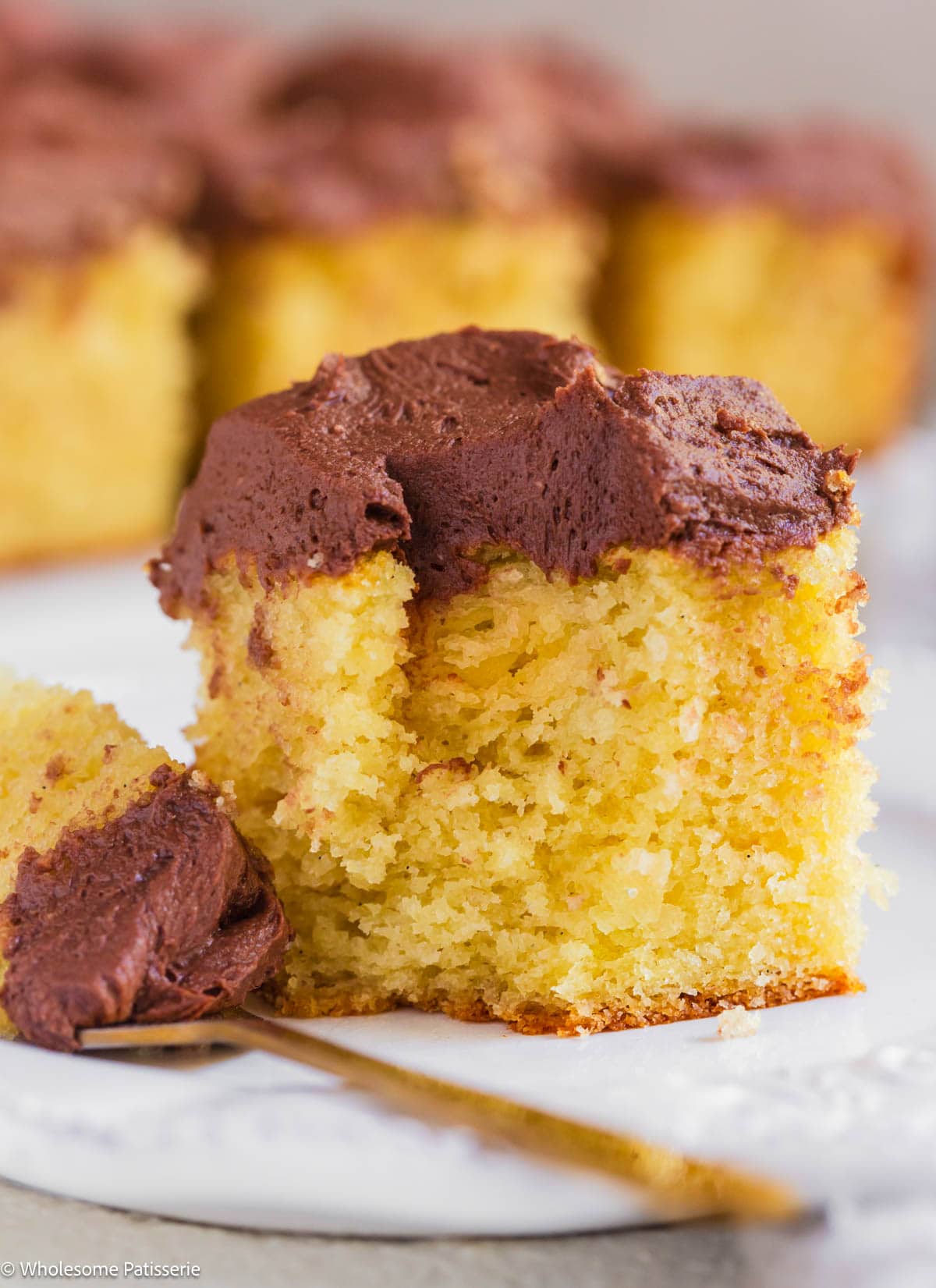 Square of yellow cake without buttermilk on plate with chocolate frosting.