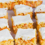Pineapple carrot cake on board cut into squares and frosted.