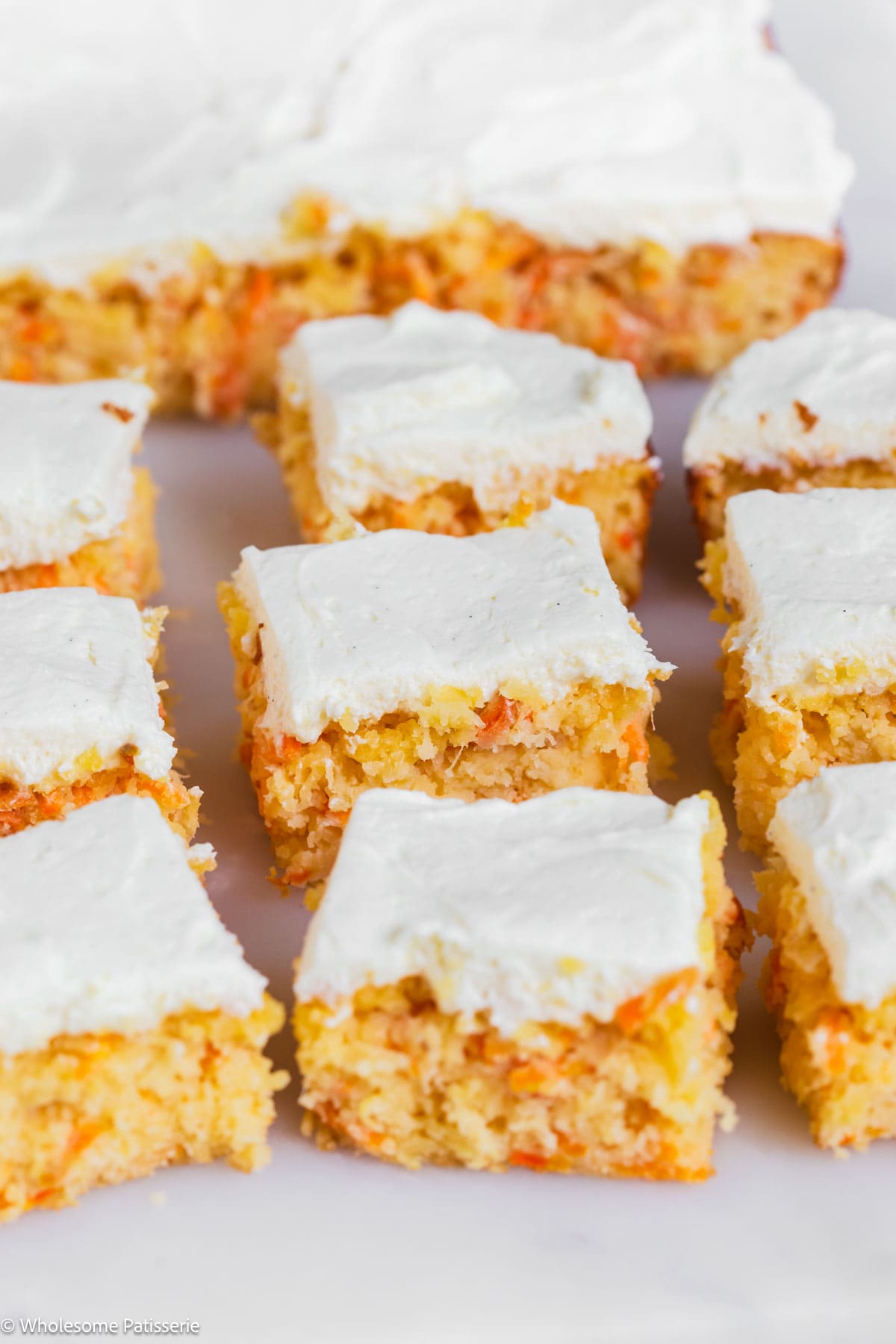 Pineapple carrot cake on board cut into squares and frosted.