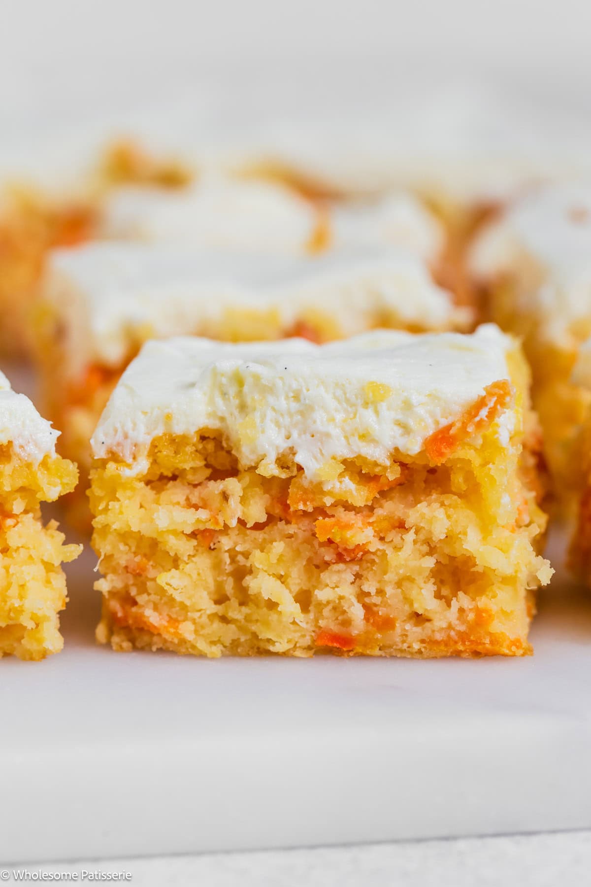 Pineapple carrot cake on board cut into squares and frosted.