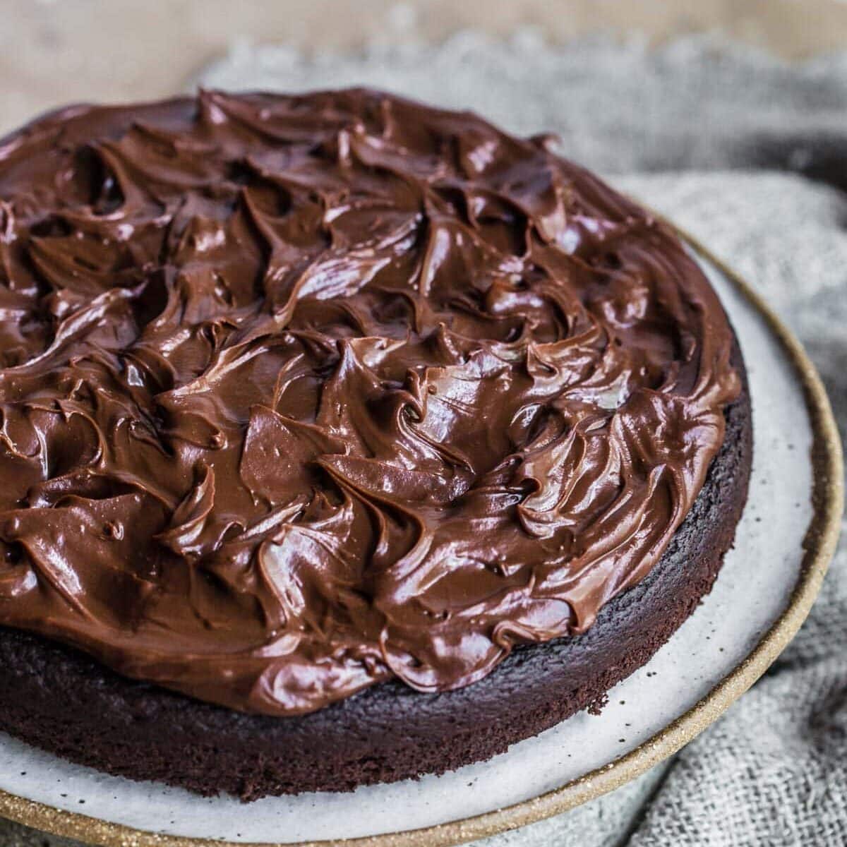 Ganache cake frosted displayed on pottery plate.