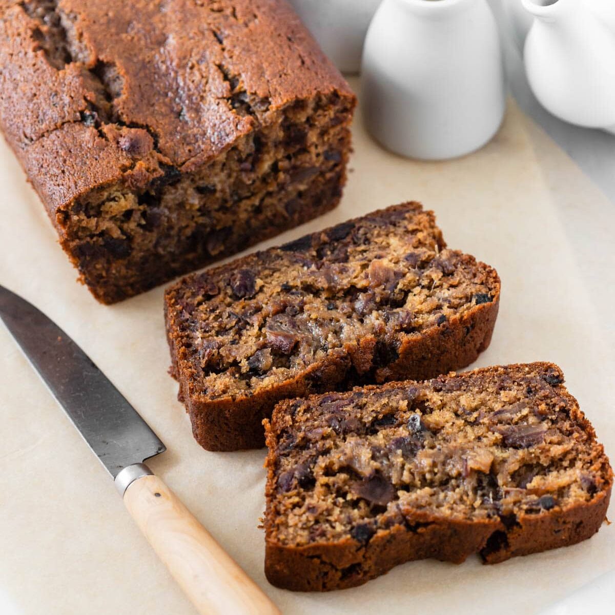 Date loaf sliced and sitting on board next to knife.
