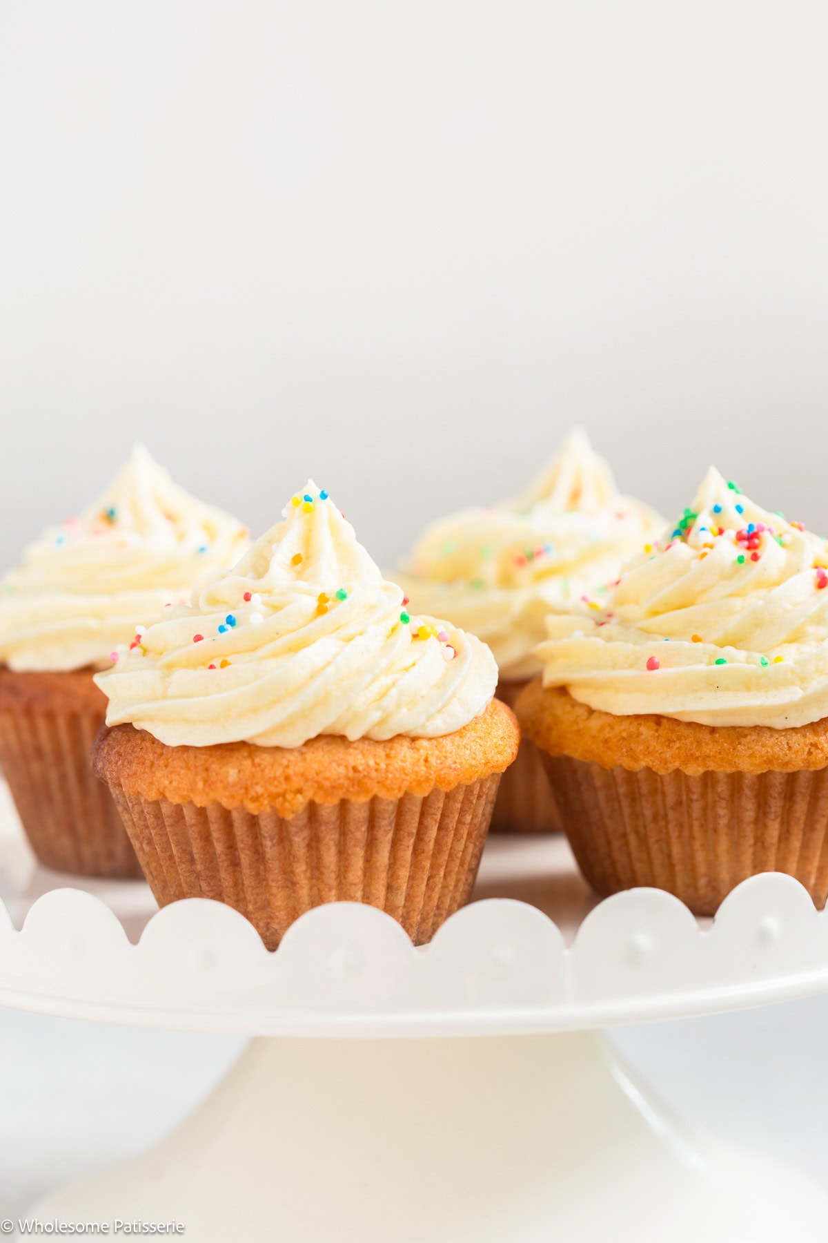 Vanilla cupcake without milk with frosting on cake stand.