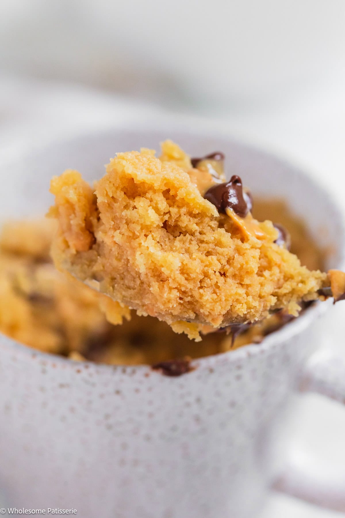 Peanut butter mug cake without milk scooped onto a spoon.