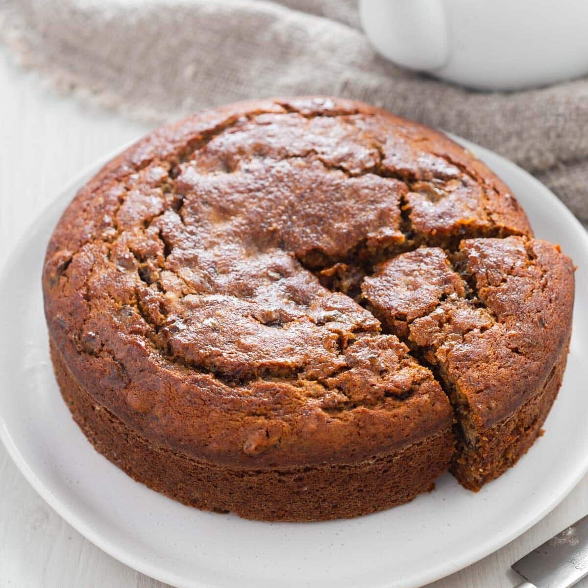 Moist date cake on plate with slice cut out.