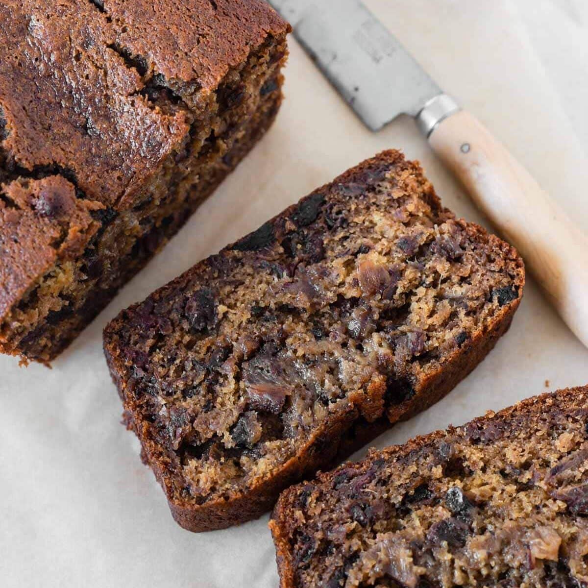 Moist date loaf sliced and sitting on parchment paper.