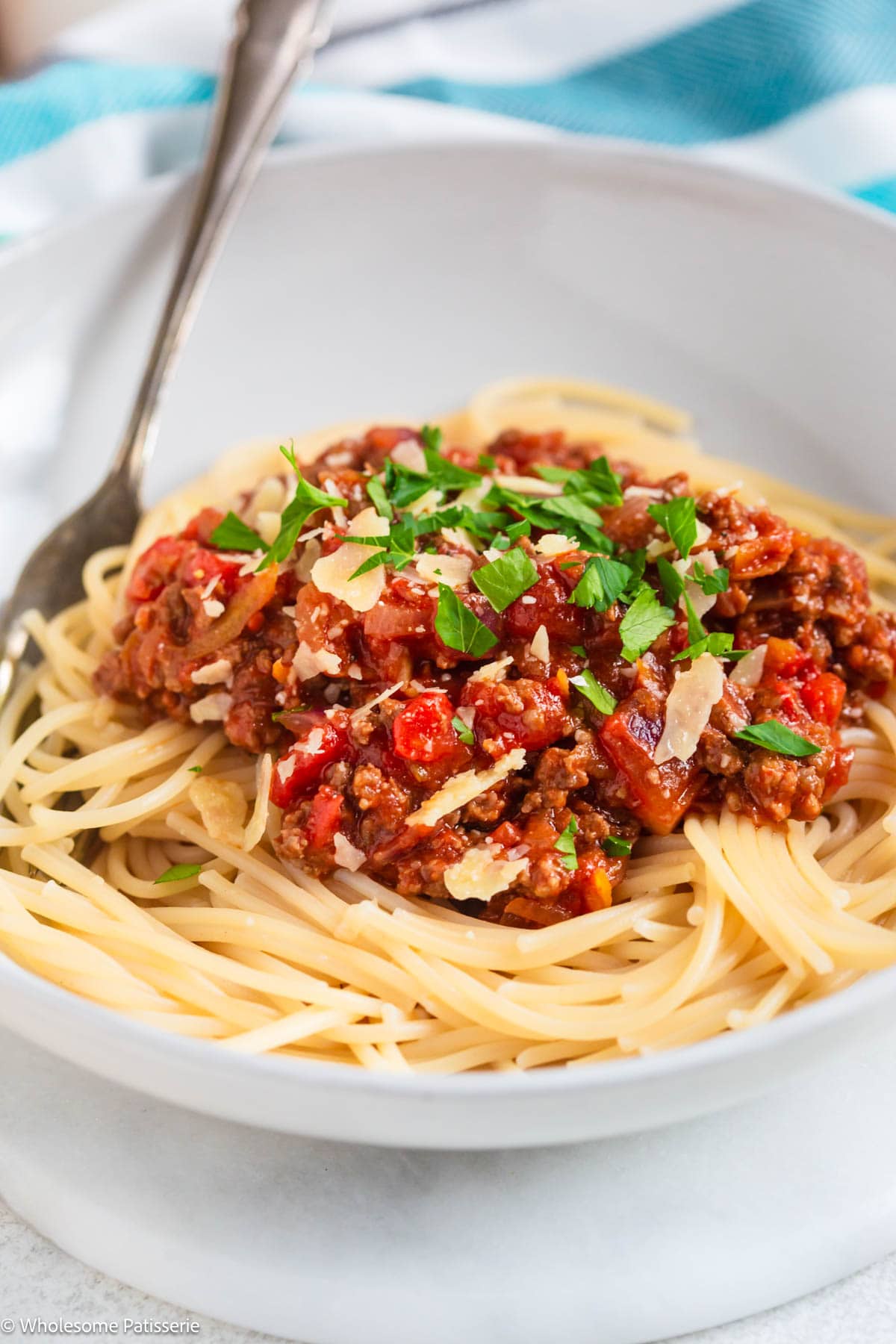 Spaghetti Bolognese served in bowl with parsley and cheese.