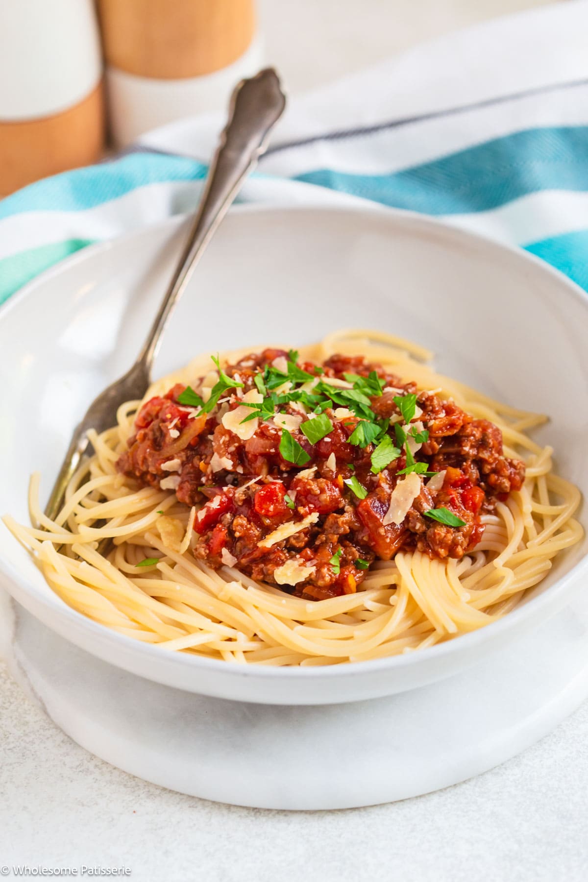 Spaghetti Bolognese served in bowl with parsley and cheese.